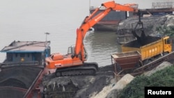An excavator transfers coal from a ship onto a truck at a coal port in Hanoi, on February 23, 2012. (REUTERS/Kham) 