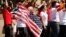 FILE - A woman holds up a U.S. flag as she other anti-deportation protesters chant in front of the White House in Washington.