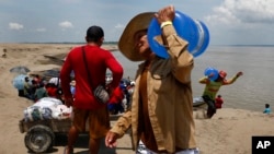 A resident of a riverside community carries a container of drinking water from an aid distribution due to the ongoing drought in Careiro da Varzea, Amazonas state, Brazil on October 24, 2023.(AP Photo/Edmar Barros)