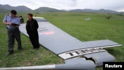 Seorang petugas tengah menanyai seorang penduduk yang berada di sekitar lokasi ditemukannya kepingan pesawat Boeing KC-135 Stratotanker, di desa Chaldovar, Kyrgyzstan (3/5). Pesawat militer AS tersebut jatuh hari Jumat (3/5), sekitar 160 kilometer dekat pangkalan udara AS, Bandara Internasional Manas, Kyrgyzstan .