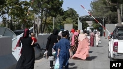 Afghans, hoping to leave Afghanistan, walk through the main entrance gate of Kabul airport in Kabul on Aug. 28, 2021.