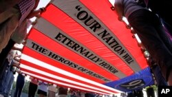 Visitors to the Flight 93 National Memorial participate in a sunset ceremony with a giant flag memorializing Flight 93, Sept. 10, 2013.