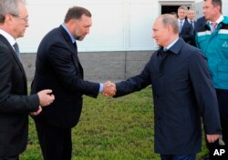 FILE - Russian President Vladimir Putin, right, shakes hands with Russian metals magnate Oleg Deripaska while visiting the RusVinyl plant in Kstovo, in Russia's Nizhny Novgorod region, Sept. 19, 2014.