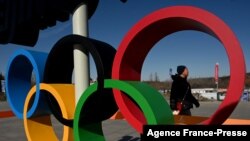 A man walks behind the Olympic Rings in Beijing on Jan. 28, 2022, ahead of the 2022 Beijing Winter Olympic Games. 