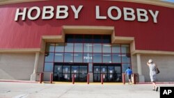FILE - In this June 30, 2014, file photo, customers walk to a Hobby Lobby store in Oklahoma City. Federal prosecutors say Hobby Lobby Stores has agreed to pay a $3 million federal fine and forfeit thousands of ancient Iraqi artifacts smuggled from the Middle East.