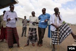 Somali Ahmed Omar Bihi and fellow refugees in Kakuma refugee camp check to see what names appear on a list for an interview with the International Organization for Migration (IOM) for potential U.S. resettlement in Kakuma, Kenya, Feb. 6, 2017. (J. Craig / VOA)