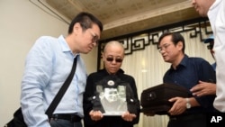 诺贝尔和平奖得主刘晓波的遗孀刘霞（中）在中国辽宁省沈阳举行的刘晓波葬礼期间手捧丈夫刘晓波的遗像。（2017年7月15日）