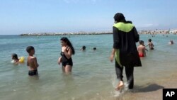 FILE - In this Aug.4 2016 file photo made from video, Nissrine Samali, 20, gets into the sea wearing traditional Islamic dress, in Marseille, southern France. The French resort of Cannes has banned full-body, head-covering swimsuits worn by some Muslim women from its beaches, citing security concerns.
