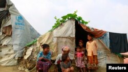 Keluarga Rohingnya duduk di depan tempat penampungan sementara mereka di sebuah kamp pengungsi saat pemerintah Myanmar memulai sebuah sensus nasional, di Sittwe, 2 April 2014. (Foto: dok).