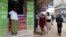 Pedestrians walk past an M-Pesa shop in downtown Nairobi, Kenya, May 12, 2009. 
