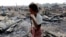 A woman walks among debris after fire destroyed shelters at a camp for internally displaced Rohingya Muslims in the western Rakhine State near Sittwe, Myanmar. 