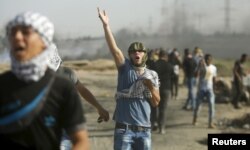 A Palestinian protester reacts to tear gas fired by Israeli troops during clashes near the border with Israel, in the east of Gaza City, Oct. 16, 2015.