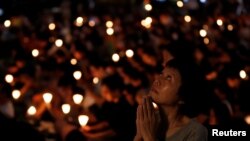 FILE - A woman reacts during a candlelight vigil to mark the 28th anniversary of the crackdown of the pro-democracy movement at Beijing's Tiananmen Square in 1989, at Victoria Park in Hong Kong, China June 4, 2017.