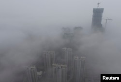 FILE - Buildings are seen shrouded in heavy haze at Qingdao development zone, Shandong province, Feb. 25, 2014.