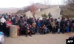 FILE - Syrians wait for the arrival of an aid convoy in the besieged town of Madaya, Jan. 11, 2016.
