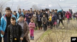 Refugees and migrants, mostly from Afghanistan, walk towards the transit center for refugees near the northern Macedonian village of Tabanovce, after being returned from Serbia, Feb. 22, 2016.