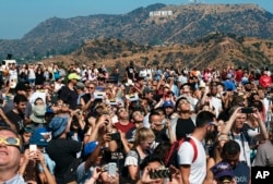 A crowd gathers in front of the Hollywood sign at the Griffith Observatory to watch the solar eclipse in Los Angeles on Monday, Aug. 21, 2017. (AP Photo/Richard Vogel)