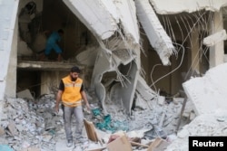 A Red Crescent aid worker inspects scattered medical supplies after an airstrike on a medical depot in the rebel-held Tariq al-Bab neighborhood of Aleppo, Syria, April 30, 2016.