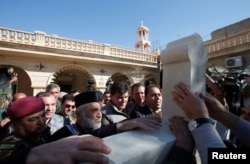 Iraqi Christians take part in a procession to erect a new cross over the Mar Korkeis church, after the original cross was destroyed by Islamic State militants, in the town of Bashiqa, Iraq, Nov. 19, 2016.