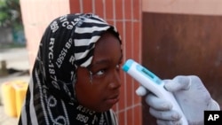 Wani Malami na amfani da na’urar auna zafin jiki domin neman alamun cutar Ebola.