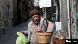 A man takes products from a basket, that were hung up so people can donate or take for free food, as Italy struggles to contain the spread of coronavirus disease (COVID-19), in Naples, Italy March 30, 2020. (REUTERS/Ciro De Luca)