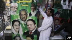 Pakistani vendors fix posters of candidates taking part in the upcoming parliamentary elections in Lahore, Pakistan, April 5, 2013.