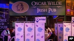 FILE - A medical professional administers a second dose of the Pfizer COVID-19 vaccine to a man at a movie theater turned into a coronavirus vaccination center in Netanya, Israel, Jan. 28, 2021.