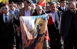 A man holds a depiction of the late Spanish dictator Gen. Francisco Franco as people gather outside Mingorrubio's cemetery, on the outskirts of Madrid, Spain, Oct. 24, 2019.