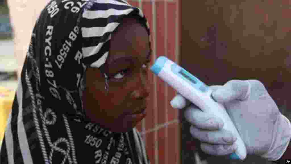 Wani Malami na amfani da na’urar auna zafin jiki domin neman alamun cutar Ebola.