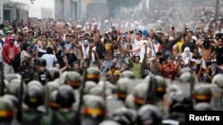 FILE - Supporters of opposition leader Henrique Capriles face off against riot police as they demonstrated for a recount of the votes in Sunday's election, in Caracas, April 15, 2013. 