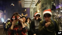 Warga mengenakan asesori untuk perayaan Natal menutup hidung dan matanya saat polisi menembakkan gas air mata untuk membubarkan para pengunjuk rasa di malam Natal di Hong Kong, 24 Desember 2019. 