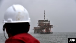 Seorang pekerja memperhatikan anjungan pengeboran gas milik ENI di Laut Adriatik, 6 April 2016. 