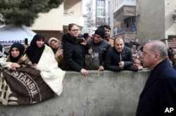 Turkey's President Recep Tayyip Erdogan speaks to people as he visits the site of a collapsed building in Istanbul, Saturday, Feb. 9, 2019.