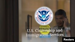 រូបឯកសារ៖ សន្តិសុខម្នាក់កំពុងនិយាយទូរស័ព្ទក្បែរច្រកចូលការិយាល័យអន្តោប្រវេសន៍ នៅទីក្រុងញូវយ៉ក កាលពីថ្ងៃទី១៥ ខែសីហា ឆ្នាំ២០១២។