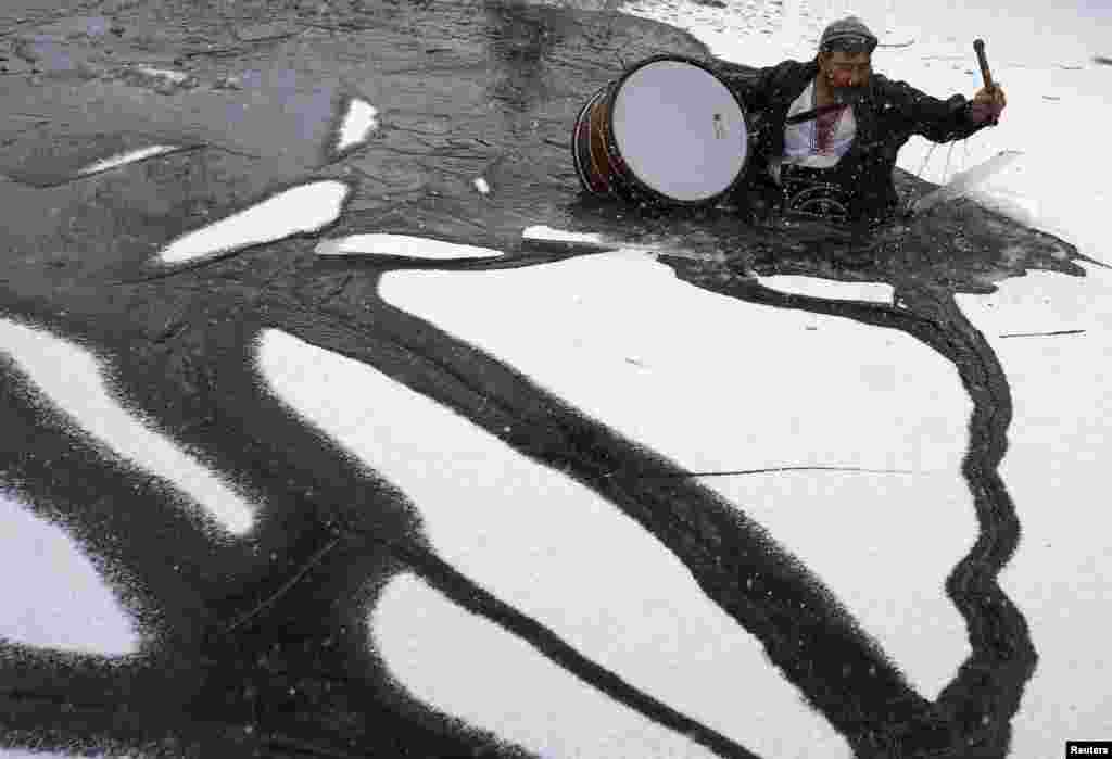 Seorang pria memecahkan es, setelah menyeberangi sungai Tundzha yang membeku, saat perayaan Hari Epiphany di kota Kalofer,&nbsp;Bulgaria. &nbsp;
