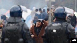 Seorang migran membetulkan penutup kepalanya saat berjalan di depan barisan polisi Bosnia di persimpangan perbatasan Maljevac, Bosnia, 26 Oktober 2018. (Foto: dok).