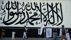 A vendor selling Taliban flags waits for customers next to a large Taliban flag in Kabul on Sept. 24, 2021.