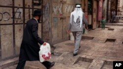 Seorang Yahudi ortodoks berjalan di belakaang seorang pria Palestina di kota tua Yerusalem (foto: ilustrasi).