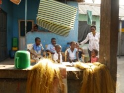 Dora Oppey, right, monitors children learning through a radio program jointly developed by Ghana's government and USAID, in Accra, Ghana, Aug. 13, 2020. (Stacey Knott/VOA)