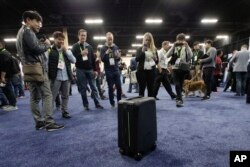 Attendees take pictures of ForwardX Robotics' CX-1 self-driving luggage during CES Unveiled at CES International Sunday, Jan. 7, 2018, in Las Vegas. (AP Photo/Jae C. Hong)