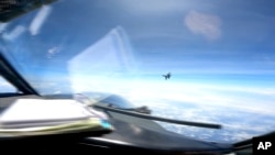 FILE - In this image from video provided by the U.S. Navy, a Chinese J-16 fighter flys aggressively close to a U.S. RC-135 aircraft flying in international airspace over the South China Sea on May 26, 2023. 