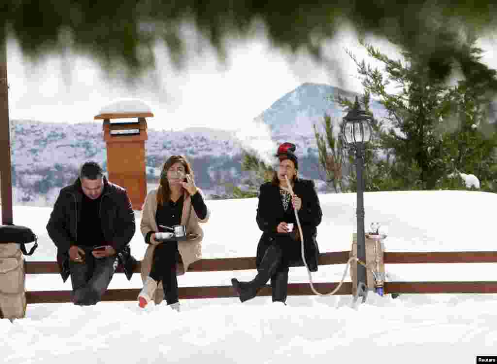 Warga Lebanon mengisap hookah (semacam tembakau melalui pipa) pada saat salju melanda kota Jizeen, Lebanon selatan.