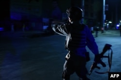 An Afghan police officer stands guard near the site of a suicide attack at the entrance to the Police Academy in Kabul, Aug. 7, 2015.