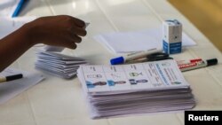 A polling assistant arranges ballot papers for voters to use at a polling station in Kigali, Rwanda, Aug. 4, 2017.