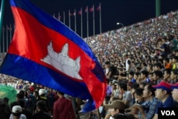 អ្នក​គាំទ្រ​កាន់​ទង់ជាតិ​ប្រទេស​កម្ពុជា​ ដើម្បី​លើក​ទឹក​ចិត្ត​ក្រុម​បាល់​ទាត់​ជម្រើស​ជាតិ​កម្ពុជា​ ក្នុង​ការប្រកួត​ជាមួយ​ក្រុម​សឹង្ហបុរី ក្នុង​ការប្រកួត​ជំរុះ​វគ្គ​បឋម​អាស៊ី​ (នូវ ពៅលក្ខិណា/VOA)