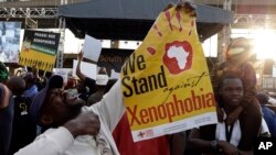 FILE - A man holds a poster reading "we stand against xenophobia" during a march in Johannesburg, South Africa, protesting against recent attacks on immigrants that killed seven people, April 23, 2015.