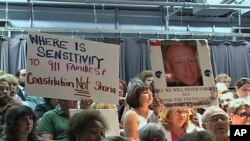 Opponents in the audience hold signs protesting plans for the Islamic center