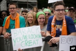 People hold posters to support U.S. President Barack Obama as they watch a discussion event on democracy and global responsibility at a Protestant conference in Berlin, Germany, May 25, 2017.