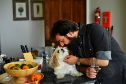 The Sharpville Show's lead singer Todd Sharpville cuddles dog Genghis as the group isolate together with their families and pets in a rented luxury estate.