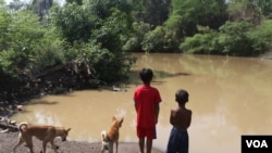 ក្មេង២នាក់ ឈរនៅមាត់ស្ទឹងអន្លង់ក្រូច ក្នុងឃុំប្រម៉ោយ ស្រុកវាលវែង ខេត្តពោធិ៍សាត់ ដែលជាកន្លែងស្ថាបនាទំនប់វារីអគ្គិសនី។ (ស៊ុន ណារិន/VOA)